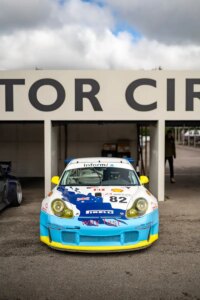 Race car Porsche 987 with distinctive lettering, stationed at track, possibly for pdk overhaul.