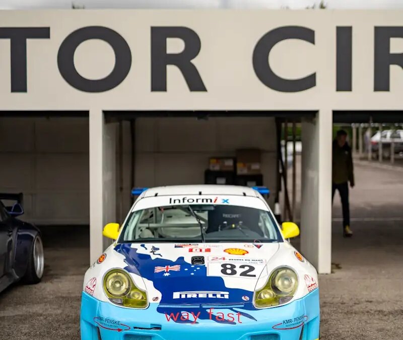 Race car Porsche 987 with distinctive lettering, stationed at track, possibly for pdk overhaul.